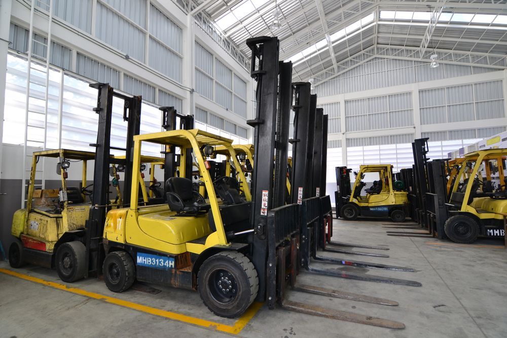 Yellow Forklifts Parked in a Warehouse, One With Tall Black Forks — Barkly Hire in Richmond, QLD