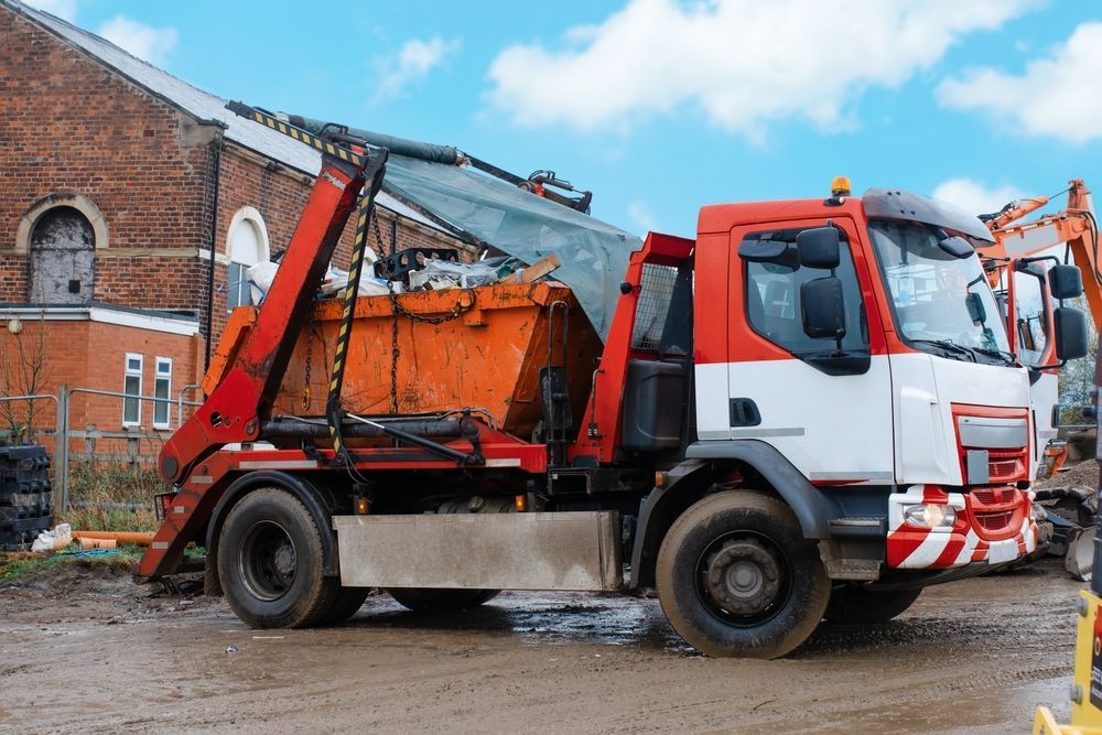 Orange-and-white Garbage Truck Parked Beside a Brick Building — Barkly Hire in Kurumba, QLD