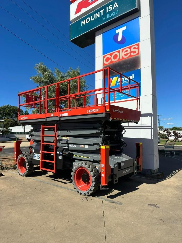 Red Scissor Lift is Parked in Front of a Coles Store — Barkly Hire in Ryan, QLD