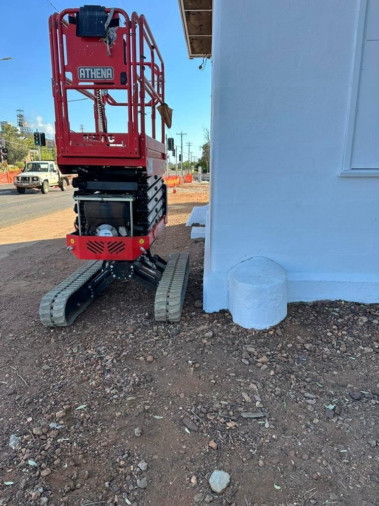 Red Scissor Lift is Parked Next to a White Building — Barkly Hire in Ryan, QLD