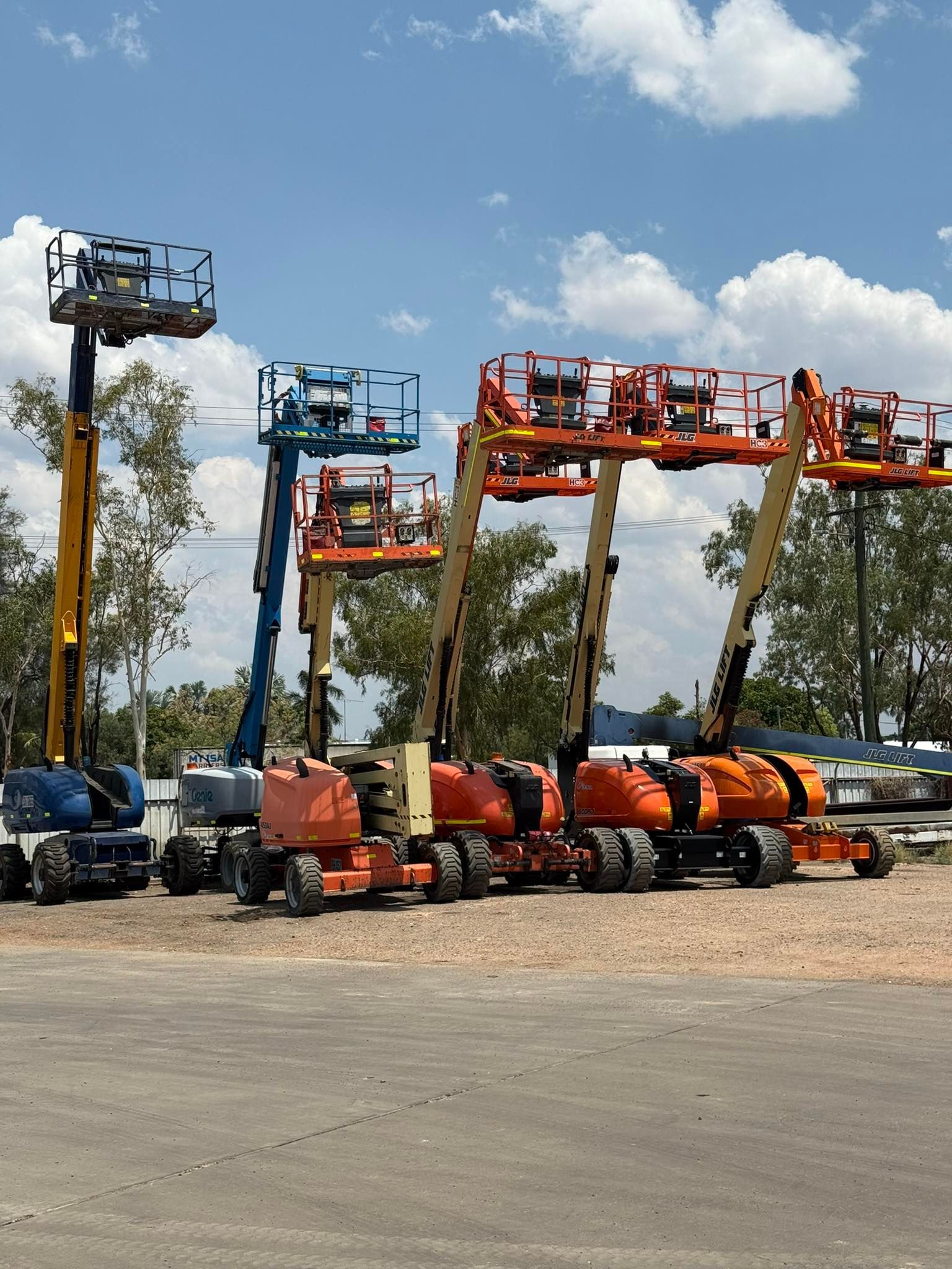 Row of Colourful Boom Lifts and Scissor Lifts Parked on a Gravel Lot — Barkly Hire in Karumba, QLD