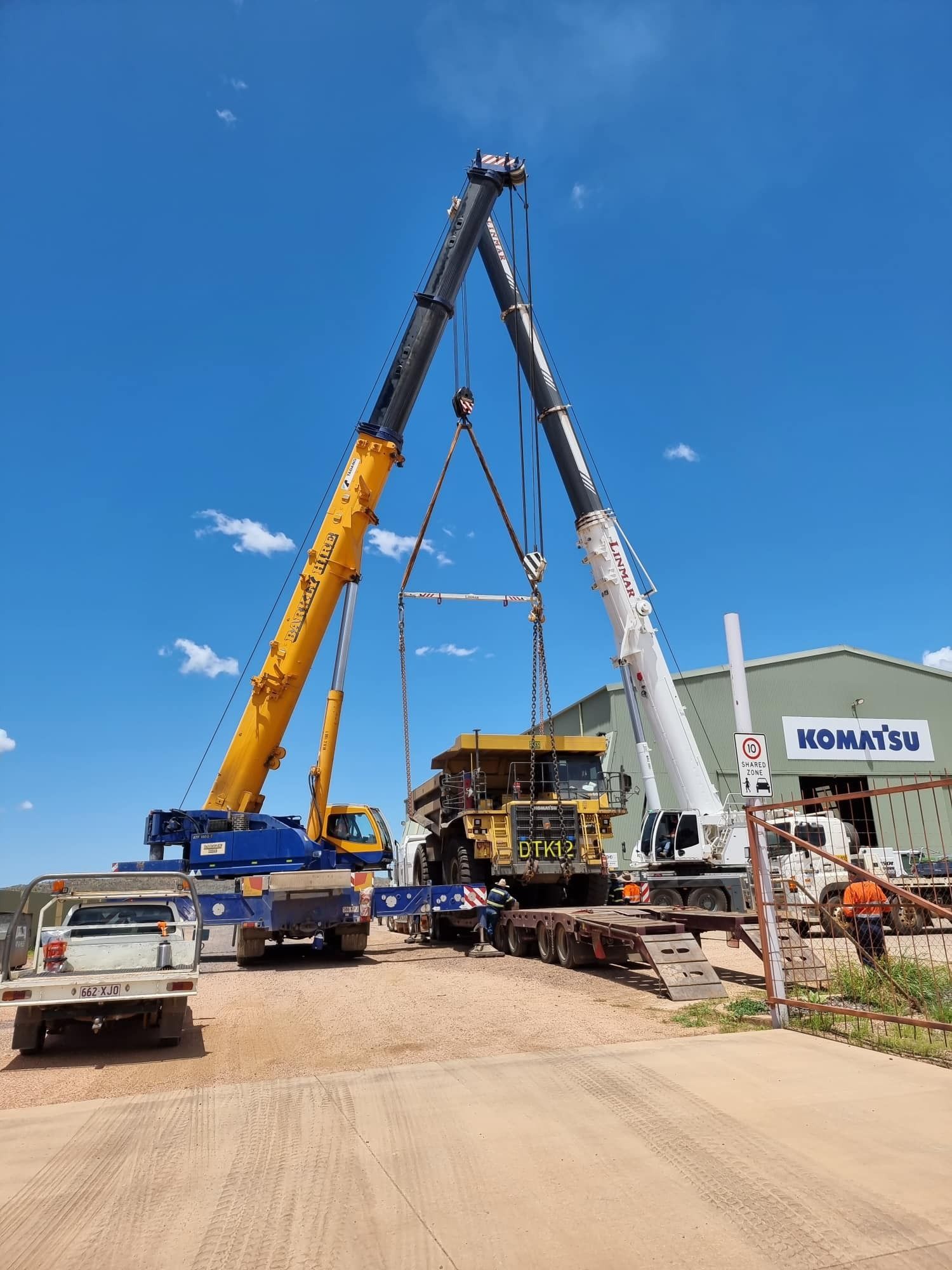 Two Cranes Are Lifting a Large Mining Truck