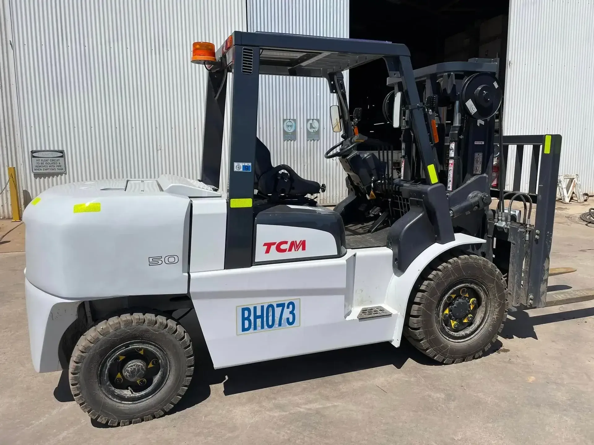 Gray TCM forklift parked outdoors beside a warehouse — Barkly Hire in Karumba, QLD