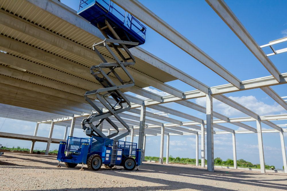Blue Scissor Lift is Sitting on Top of a Building Under Construction — Barkly Hire in Ryan, QLD