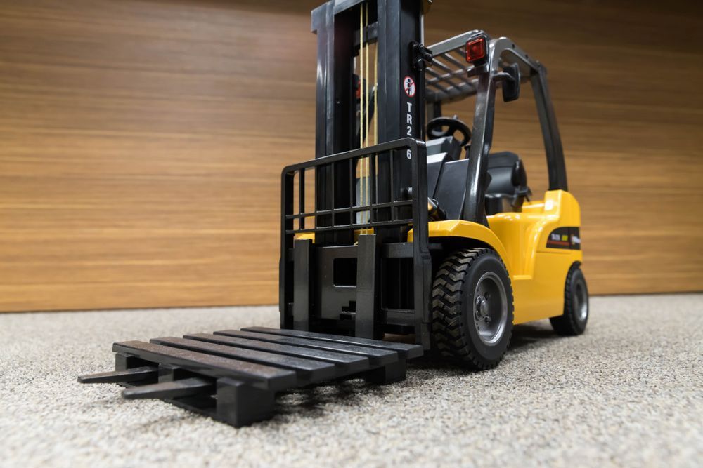 Toy Forklift is Sitting on the Floor Next to a Wooden Wall — Barkly Hire in Ryan, QLD