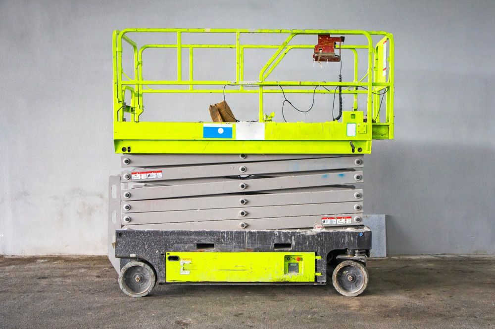 Green Scissor Lift is Sitting in Front of a White Wall — Barkly Hire in Ryan, QLD
