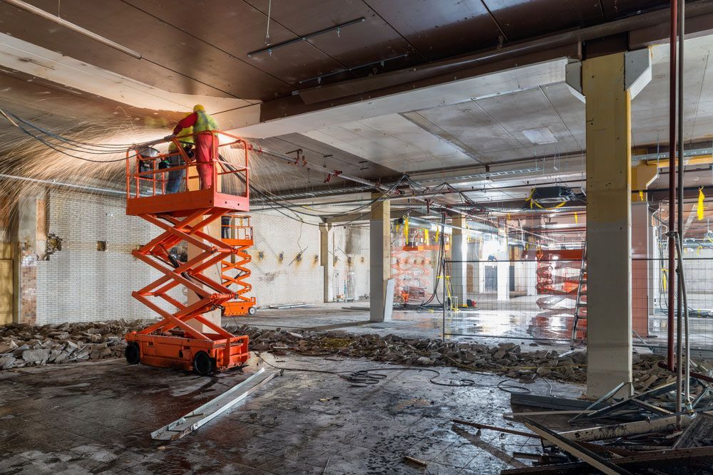 Man is Working on a Scissor Lift in an Empty Building — Barkly Hire in Ryan, QLD