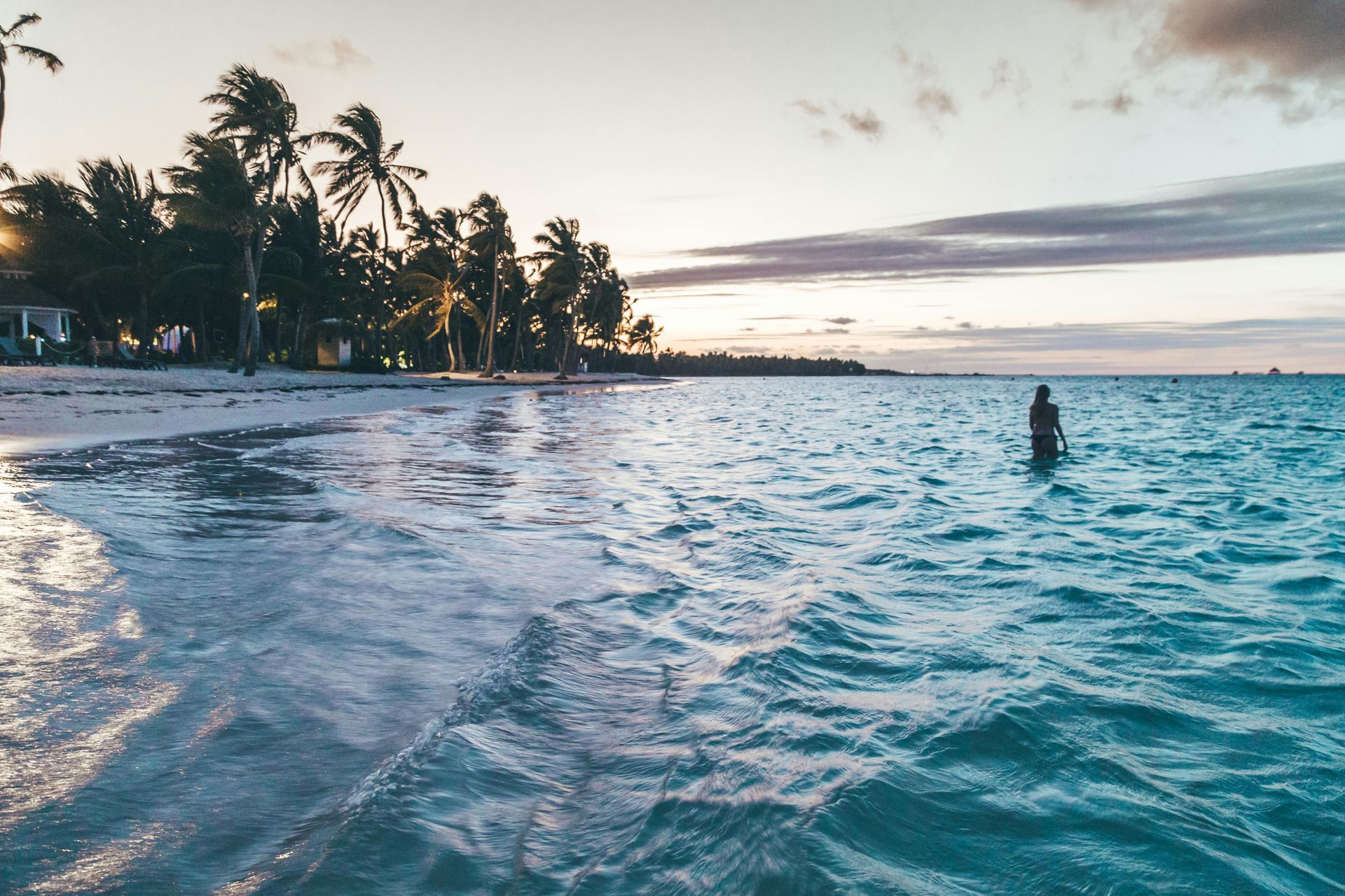 A person is standing in the ocean near a beach.
