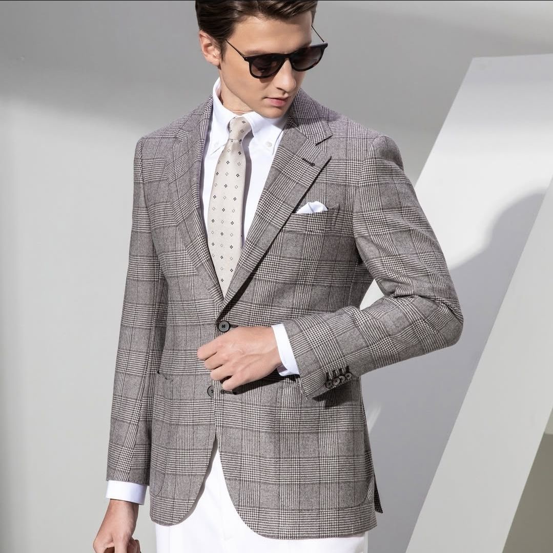 A man wearing sunglasses and a plaid suit jacket