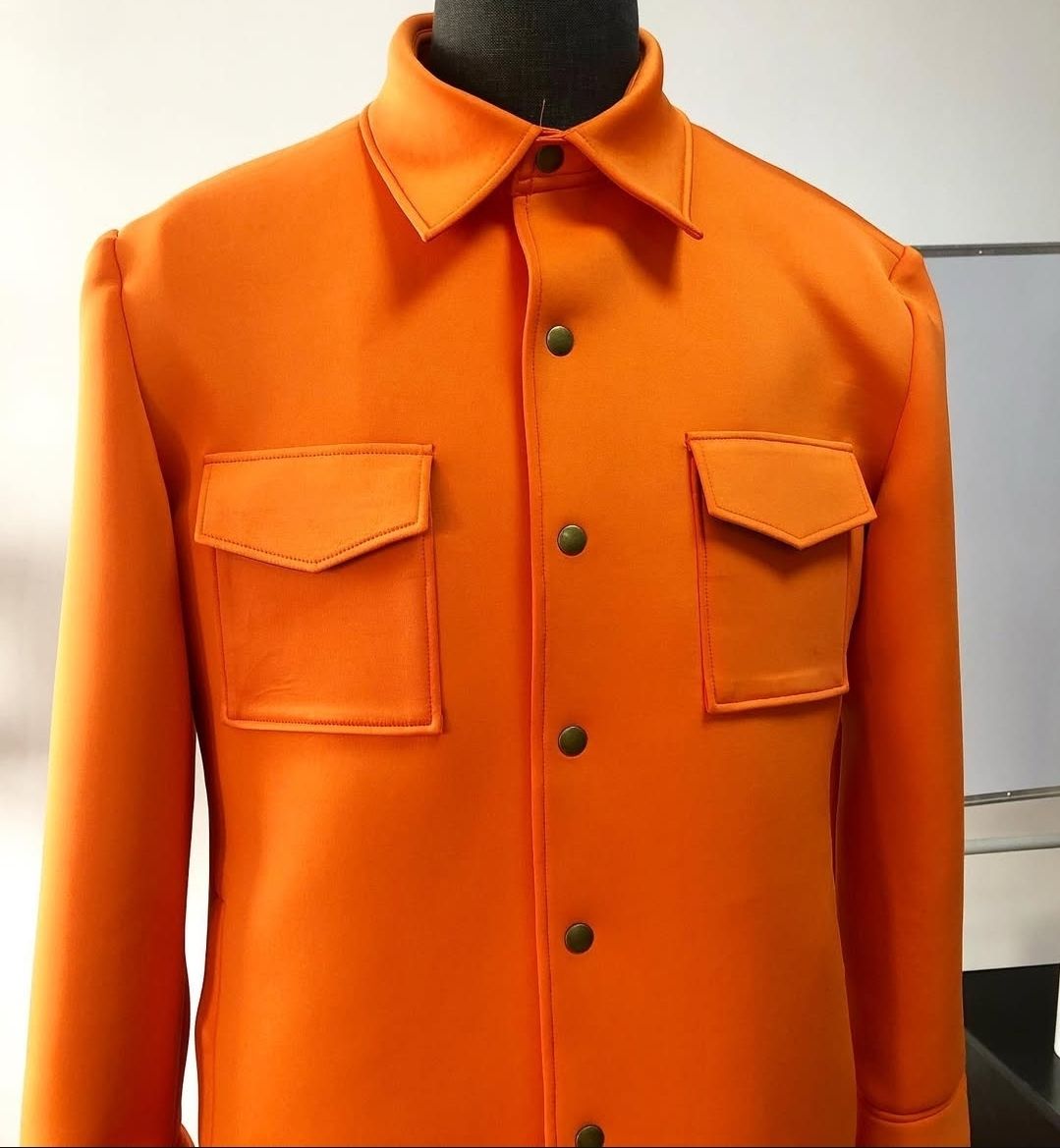 A mannequin is wearing an orange shirt with black buttons