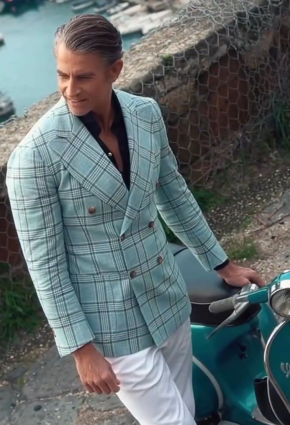 A man in a suit is standing next to a scooter