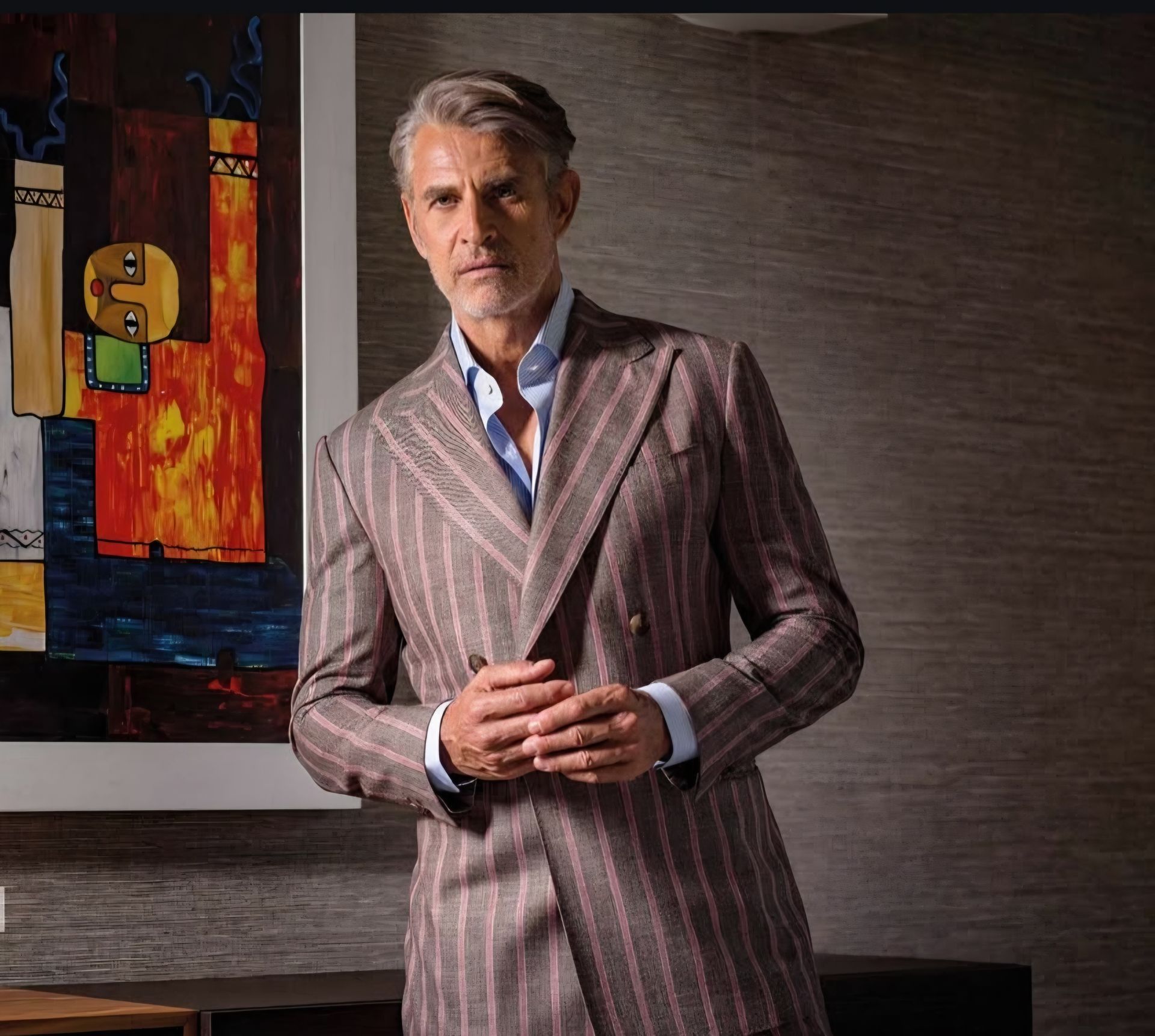 A man in a suit is standing in front of a painting