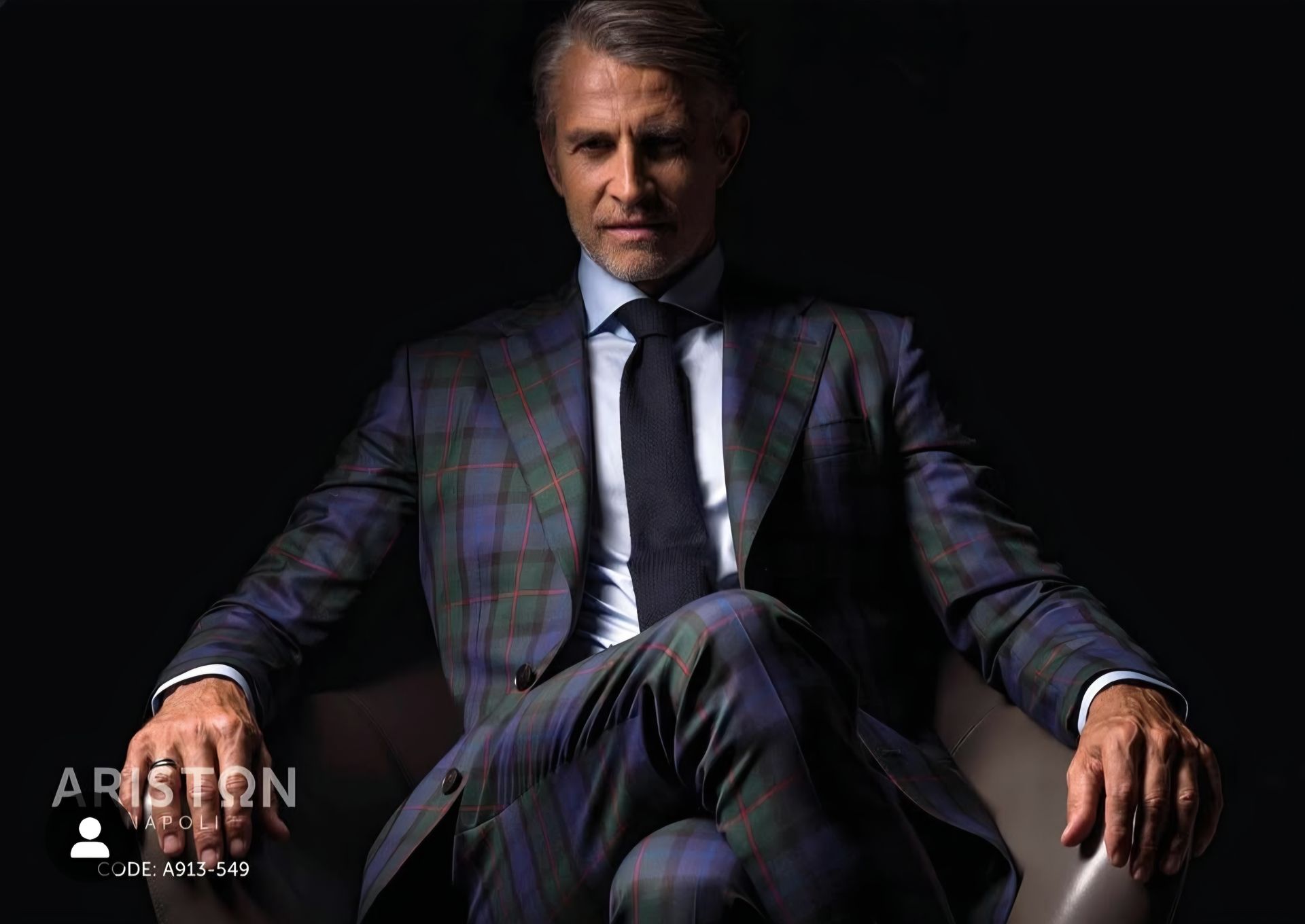 A man in a suit and tie is sitting in a chair.