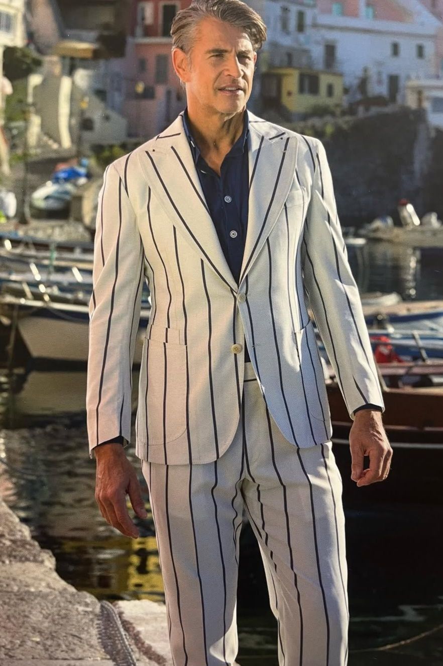 A man in a striped suit is standing next to a body of water