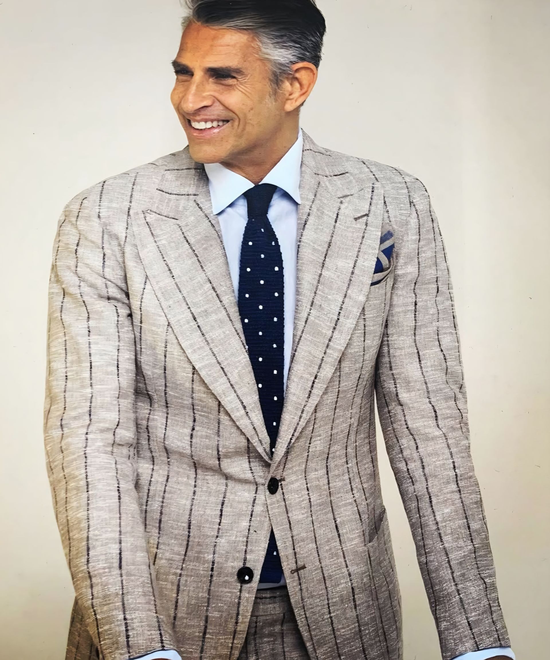 A man wearing a suit and tie is smiling