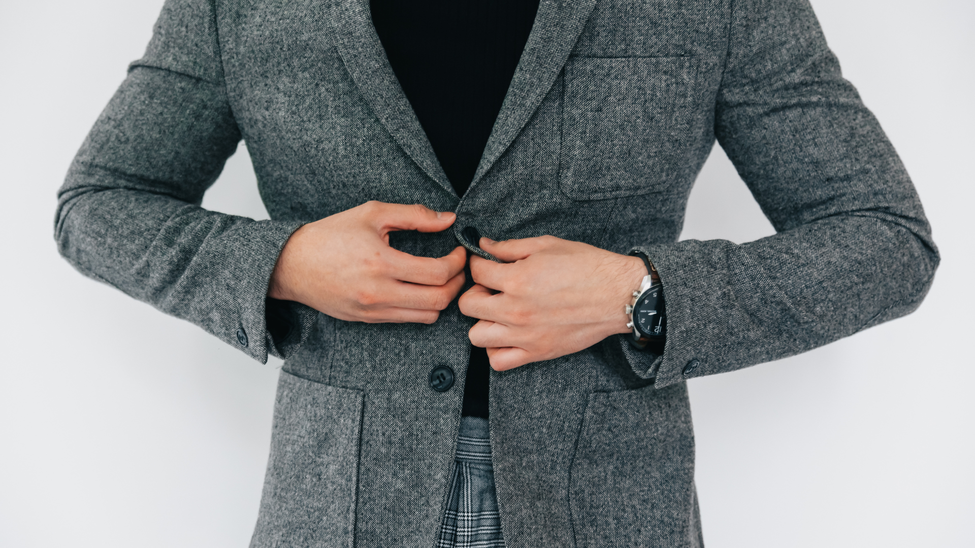 A man is adjusting his jacket with his hands.