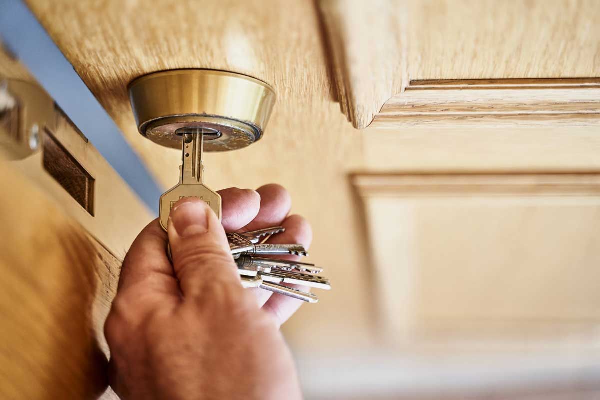 A person is holding a key in front of a wooden door.