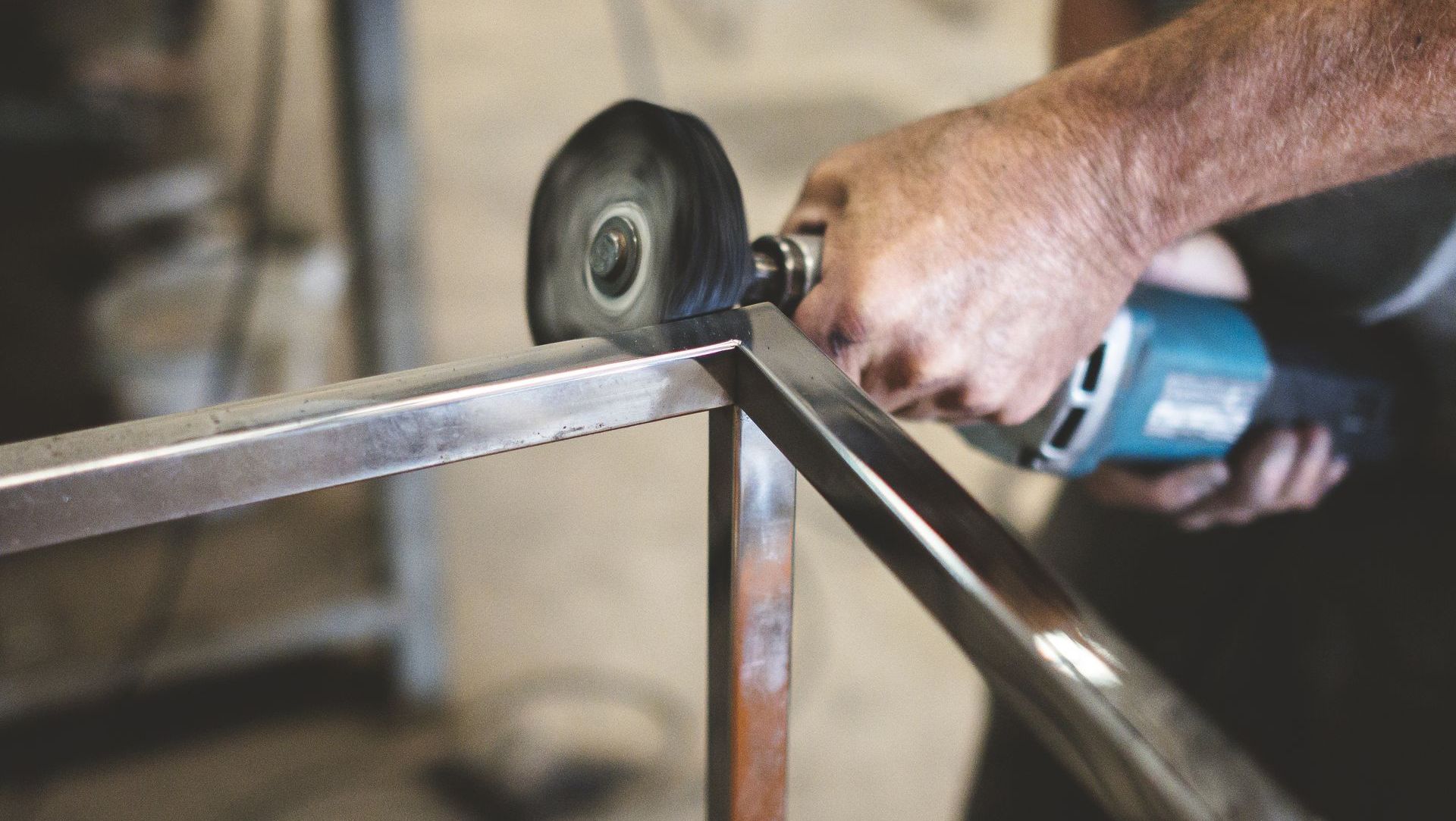 Un homme coupe un morceau de métal avec une meuleuse.