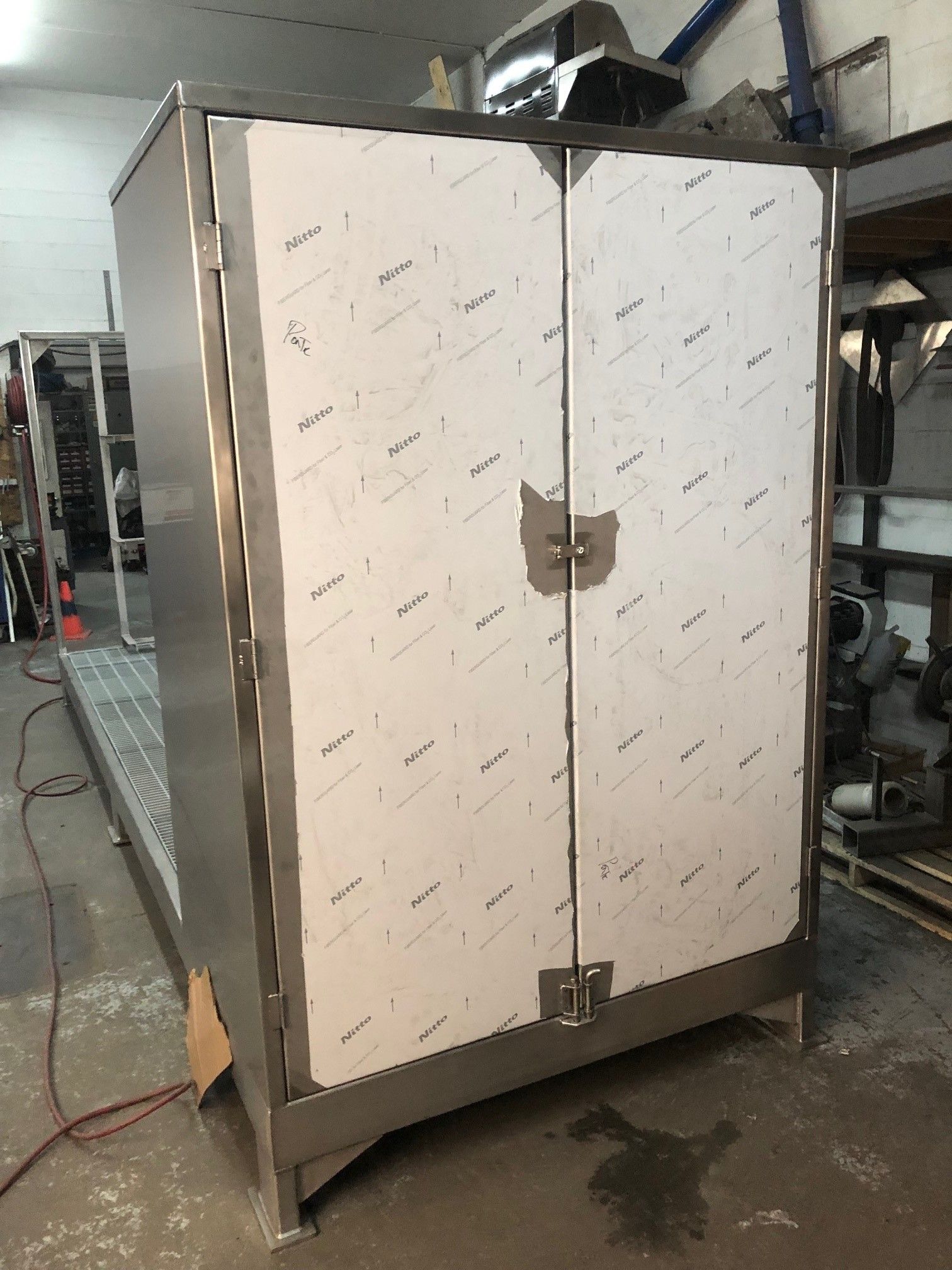 Une armoire en acier inoxydable avec deux portes est posée dans une pièce.