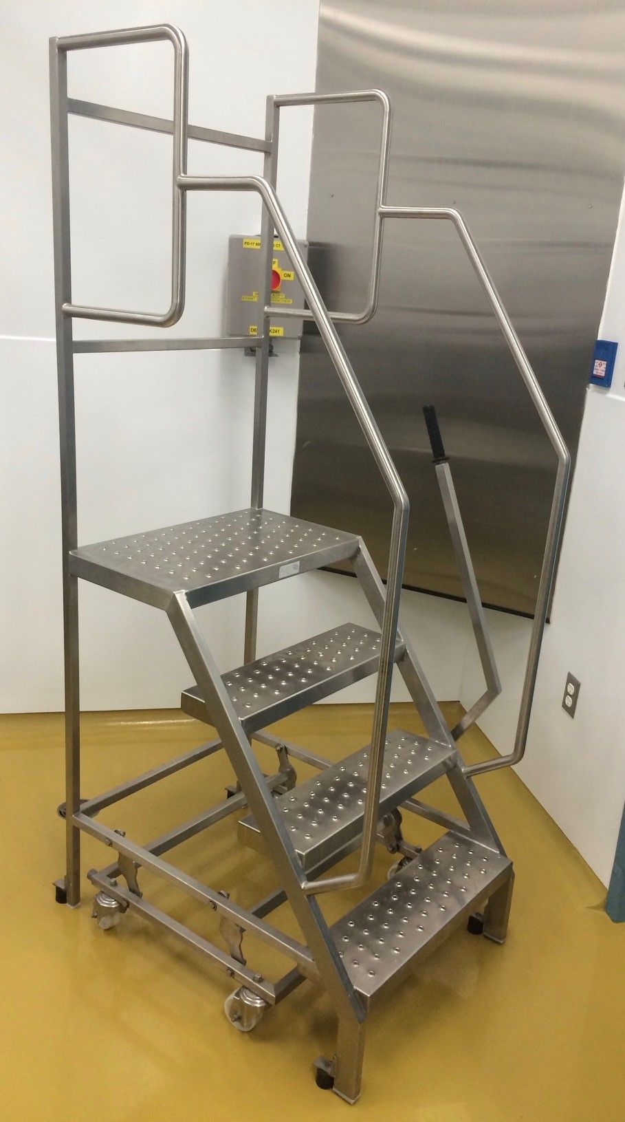 Une échelle en acier inoxydable avec des roues se trouve dans une pièce.