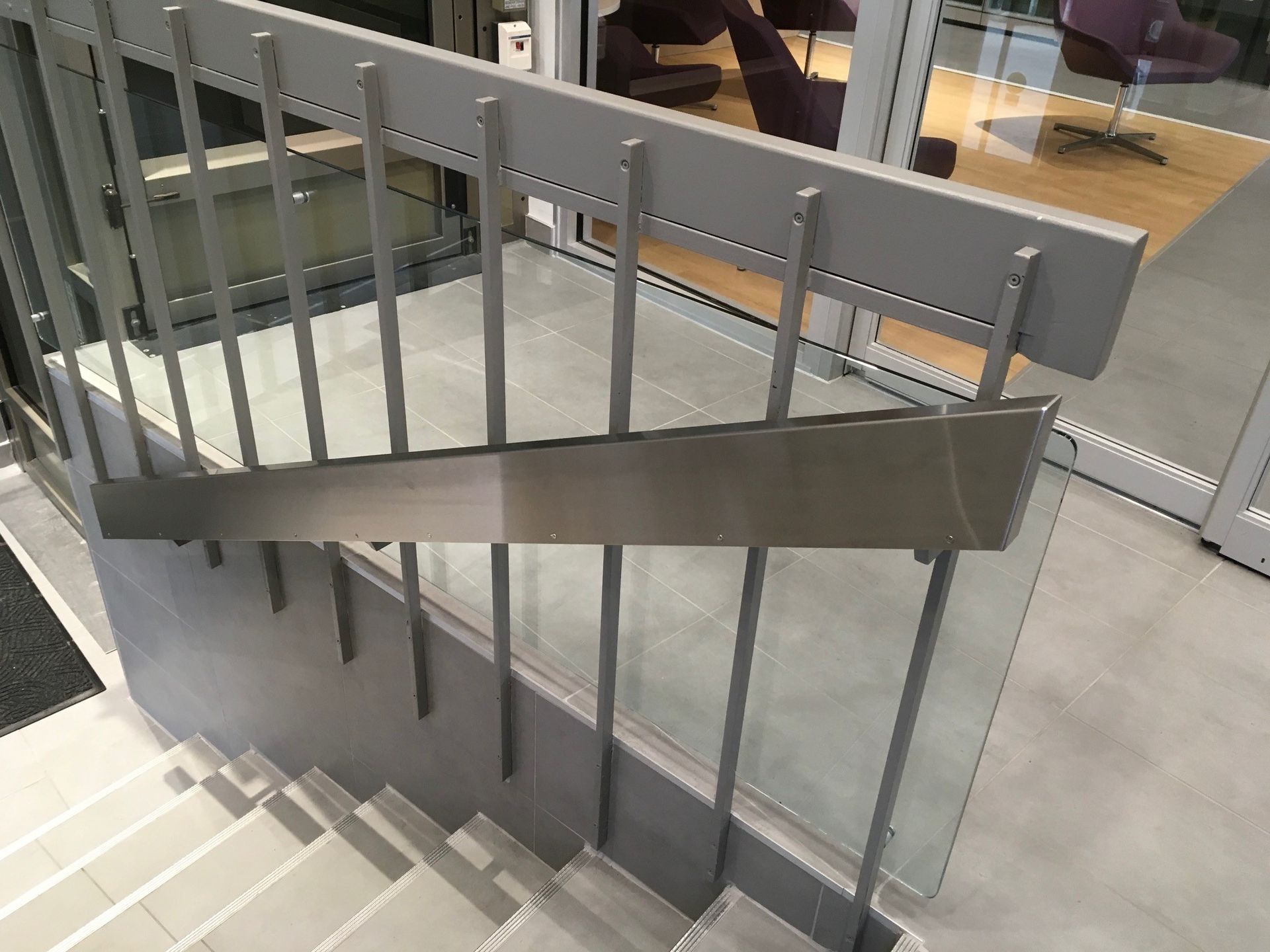 Un escalier avec une rampe en acier inoxydable et une rampe en verre