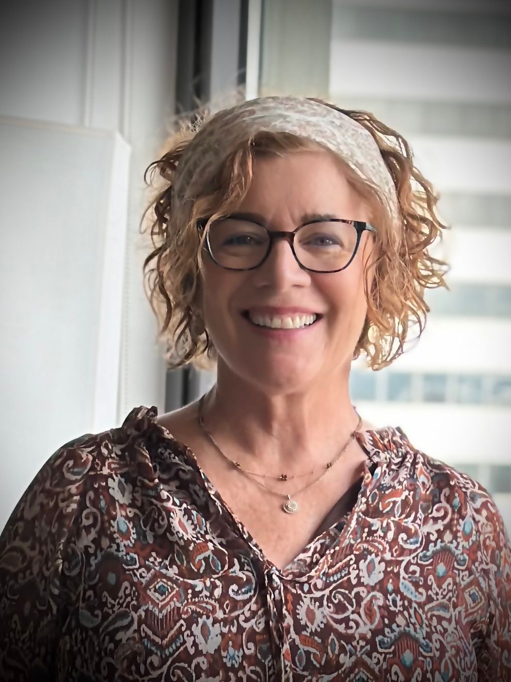 A young woman with long blonde hair and blue eyes is wearing a blue sweater.
