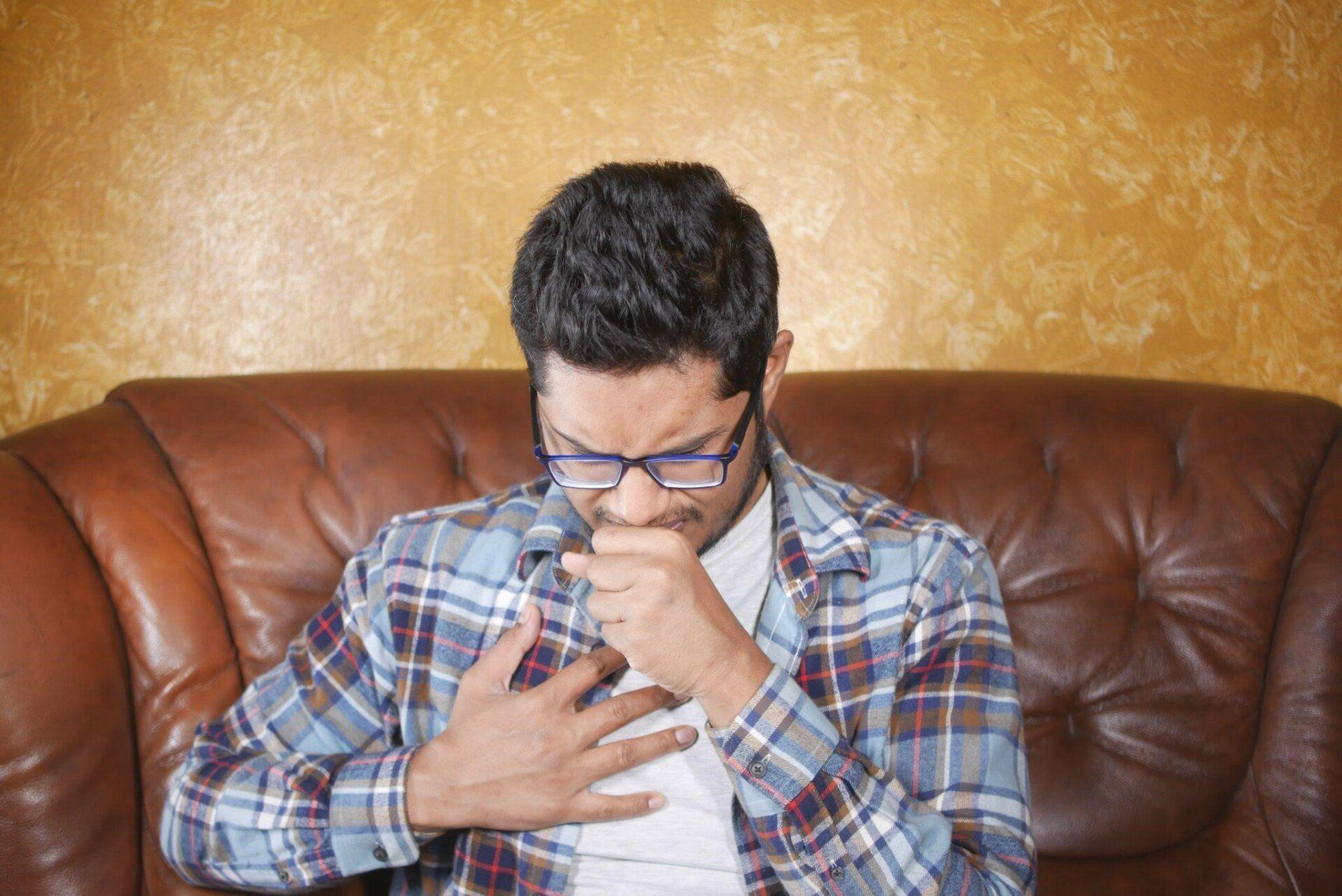A man holding his chest while coughing non-stop