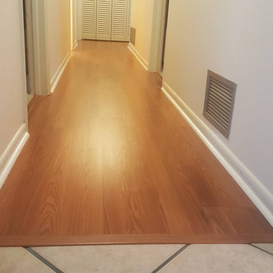 Long hallway with wood-look flooring and white trim. Air vent on right wall. Doorways on either side.