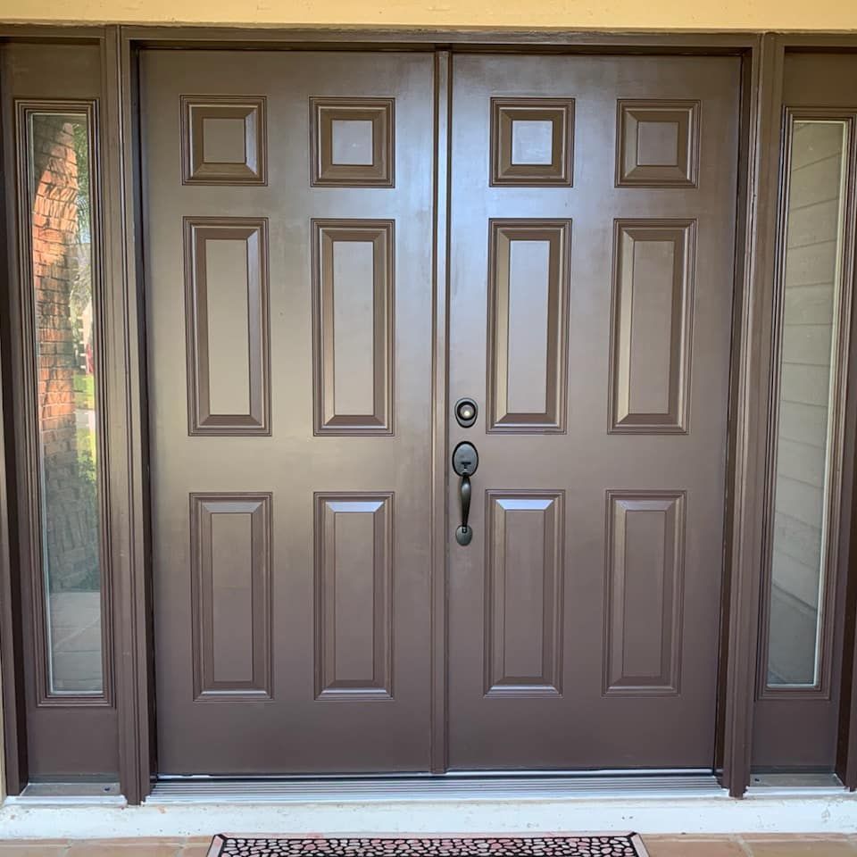 Brown double doors with side windows in an entryway.
