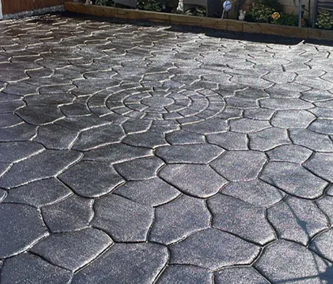 Stamped concrete driveway with a dark, textured stone pattern.