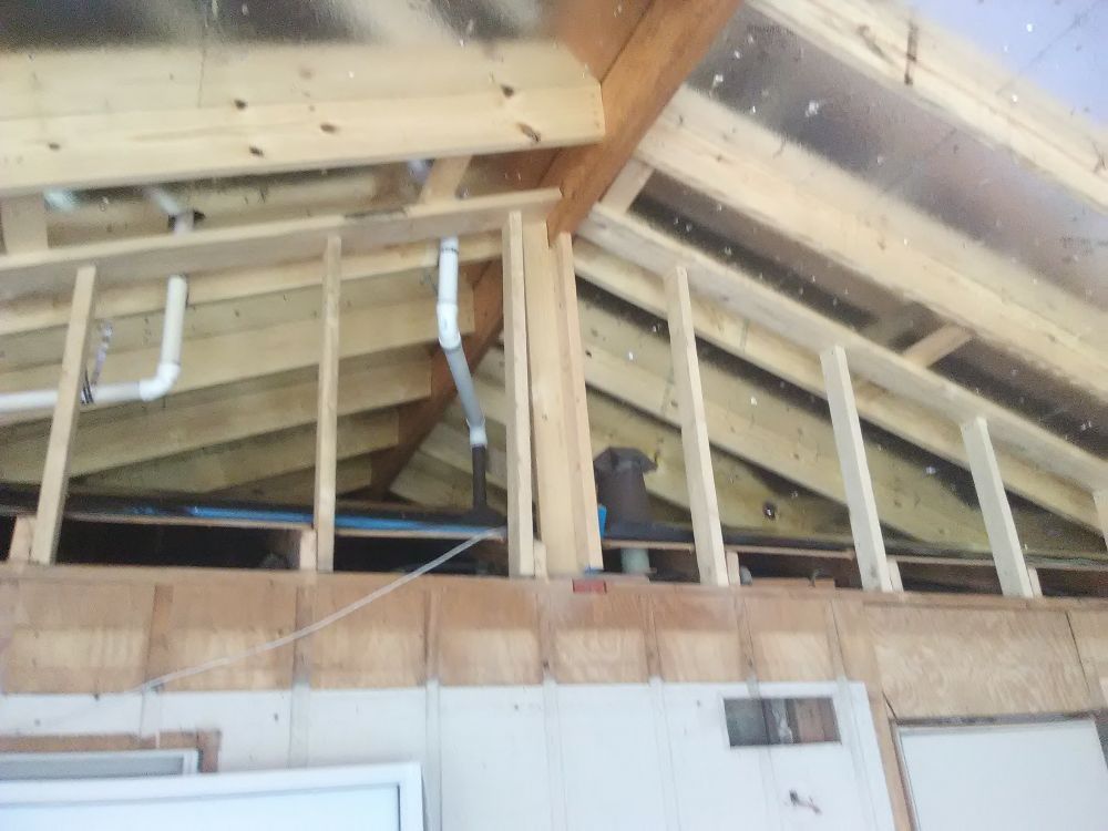 Wooden building frame with plumbing pipes installed.