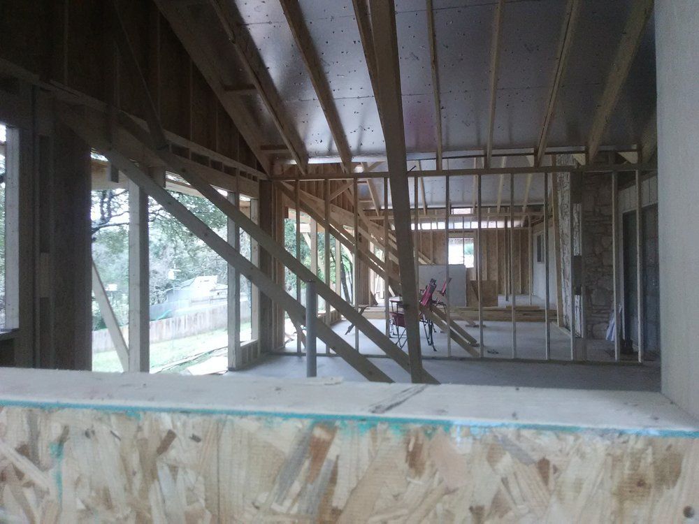 Interior view of house under construction with exposed wooden framing and partial walls.
