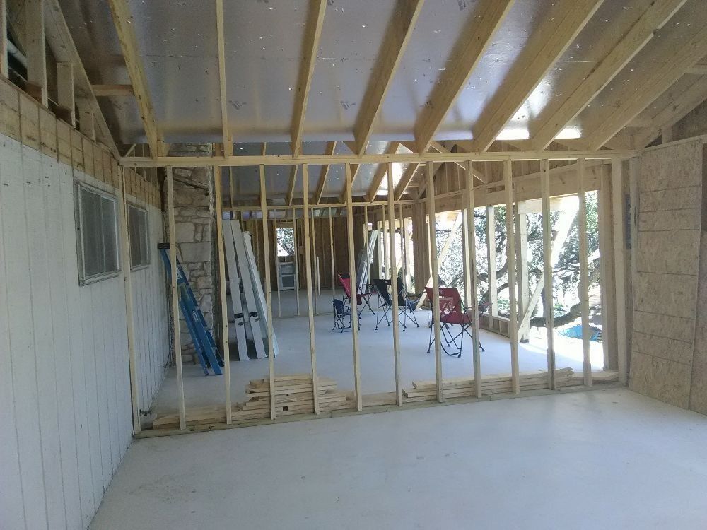 Interior view of a room under construction with exposed wooden framing and partial drywall.