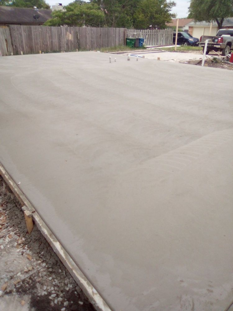 Newly poured concrete slab; gray, smooth surface. Wood framing along the edge, outdoors.