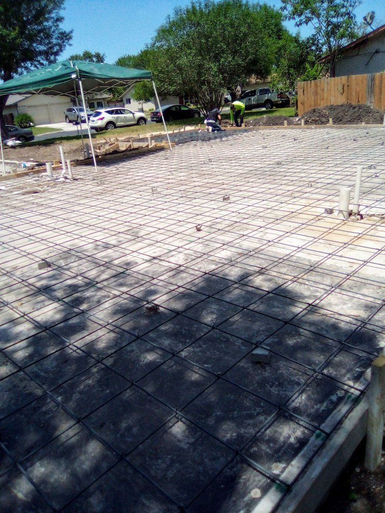 Concrete foundation with rebar grid prepared for pouring. Construction site with workers, sunny day.