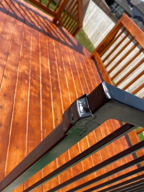 Black metal railing corner on a stained wood deck, view from above.