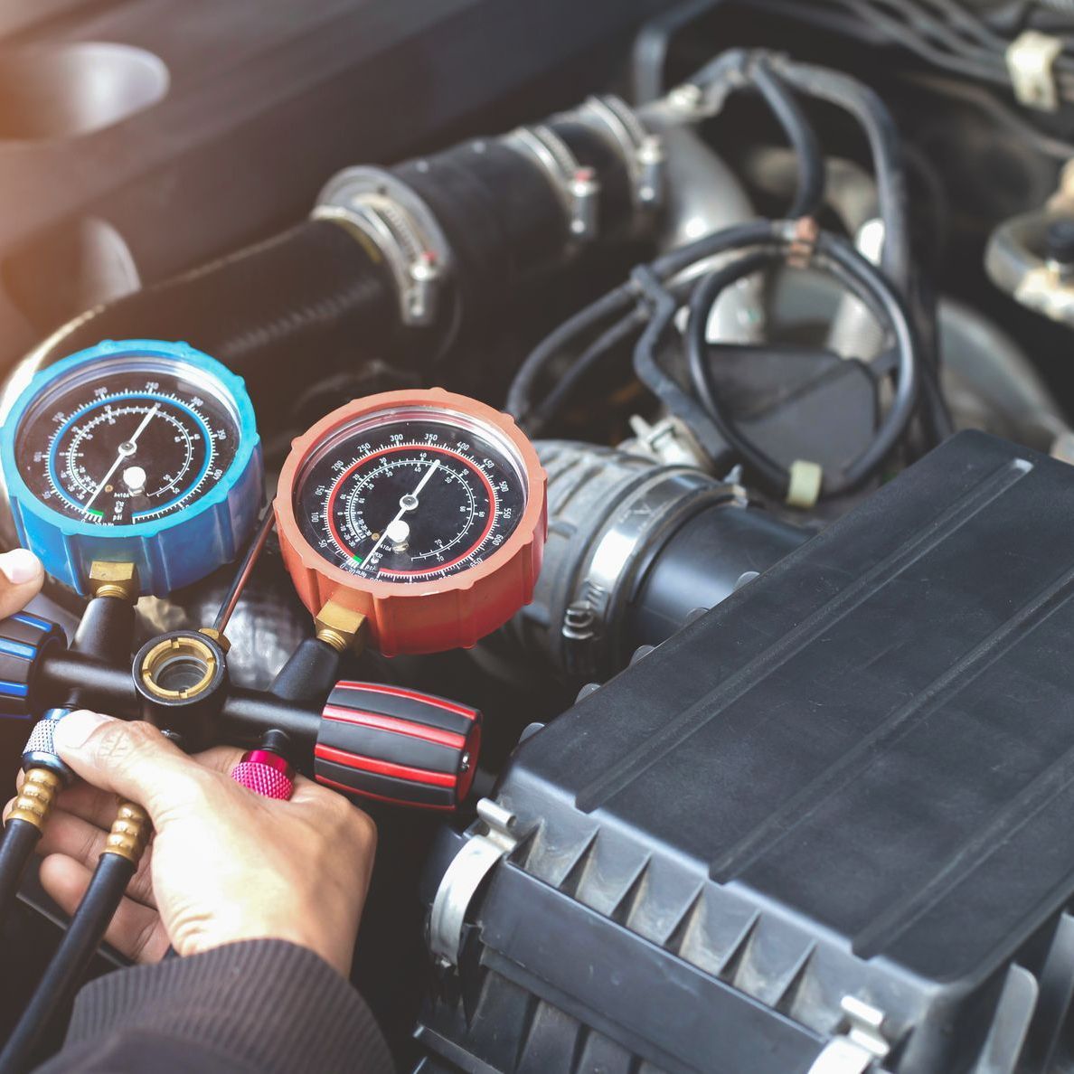 A person is working on the air conditioning system of a car