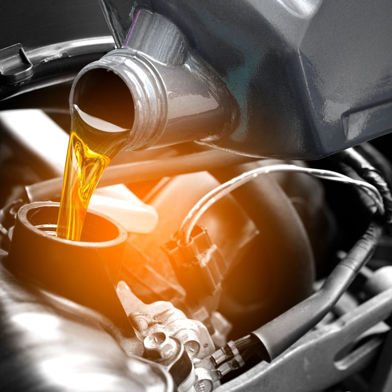 A close up of a person pouring oil into a motorcycle engine