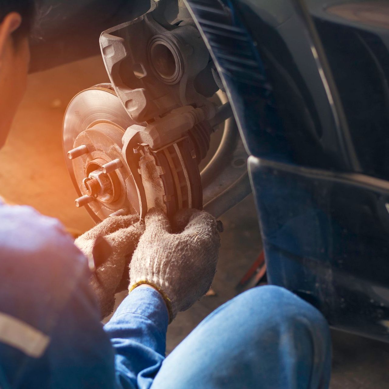A man is working on the brake pads of a car.