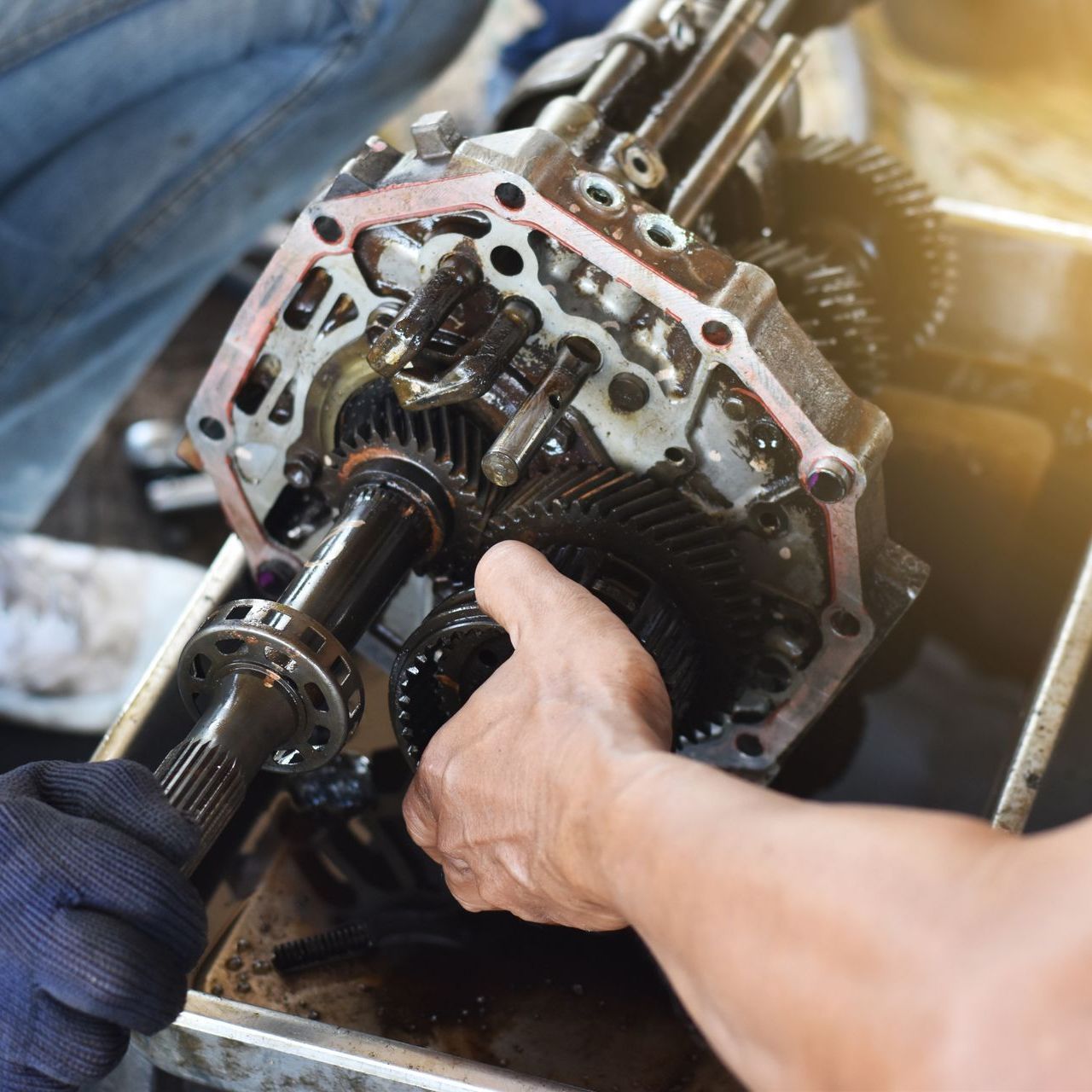 A man is working on a gearbox in a garage.