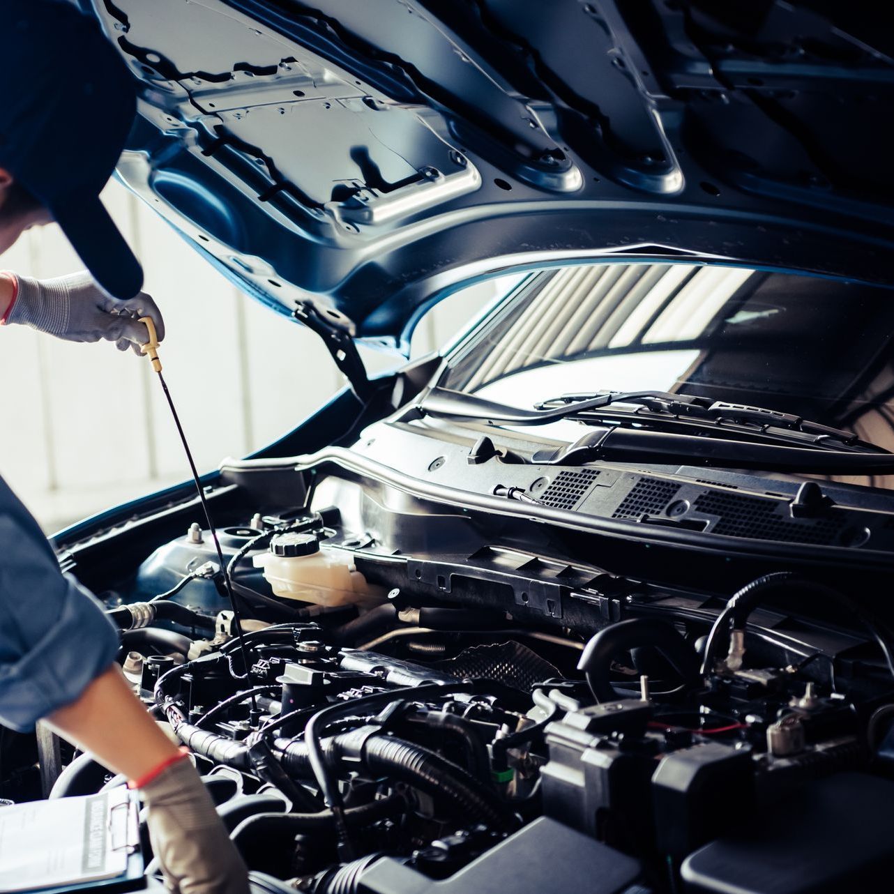 A man is looking under the hood of a car.
