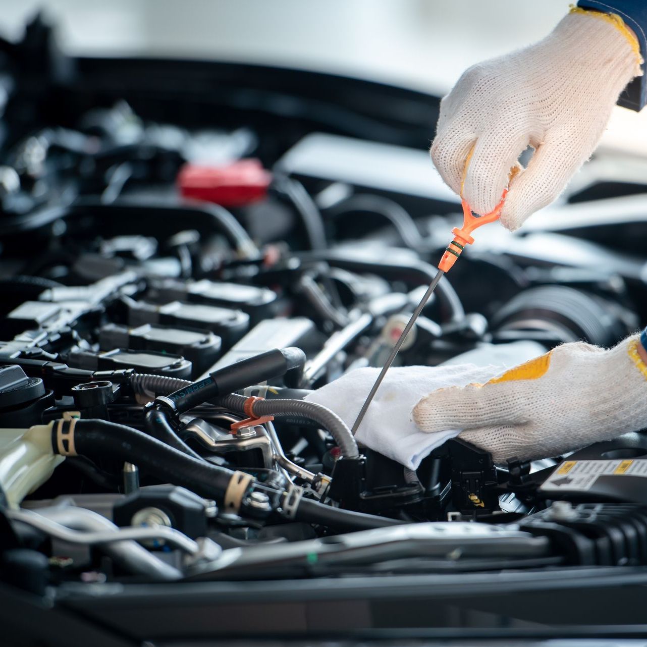 A person is checking the oil level of a car with a dipstick.