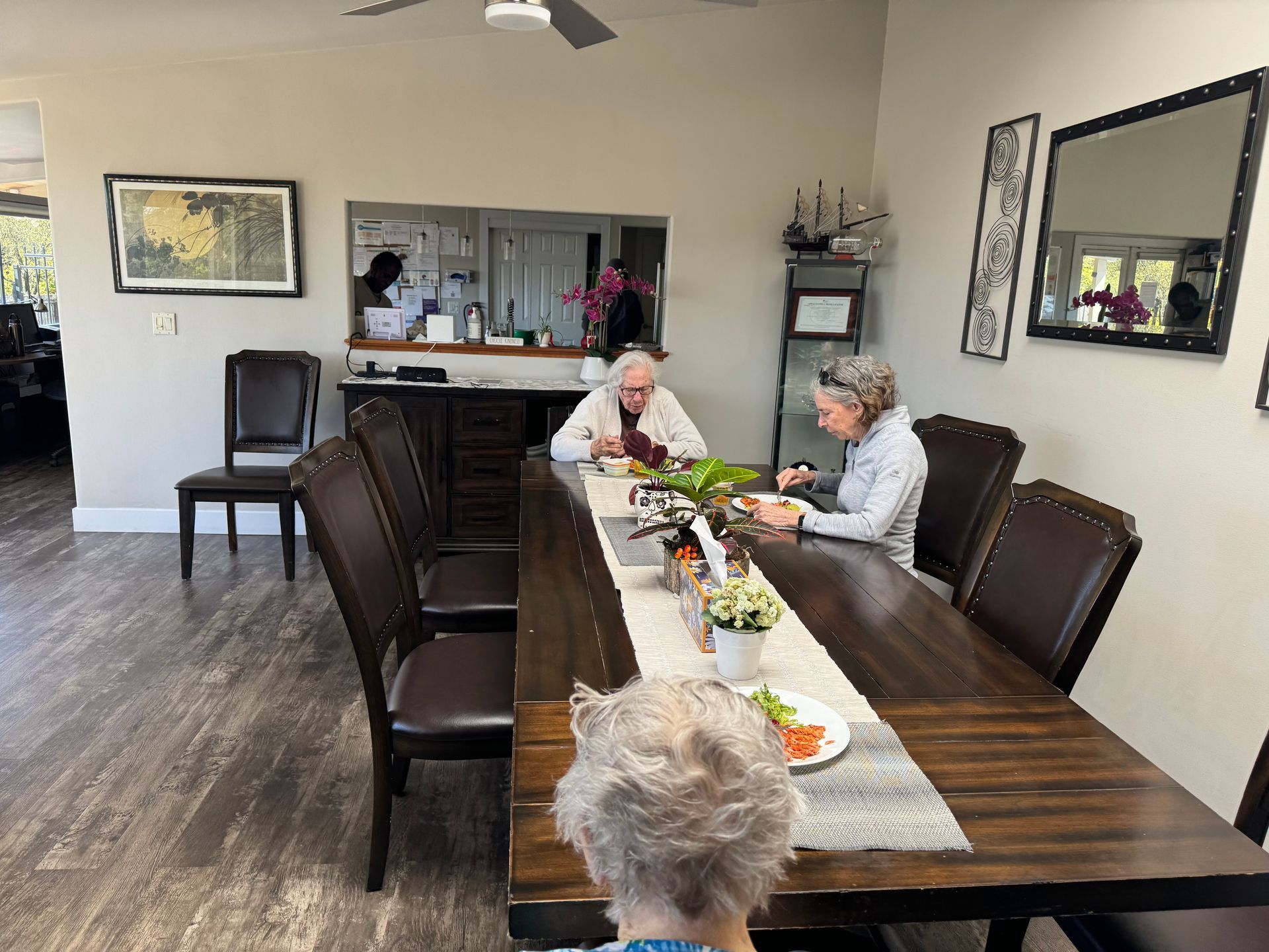 A group of people are sitting at a long table in a dining room.