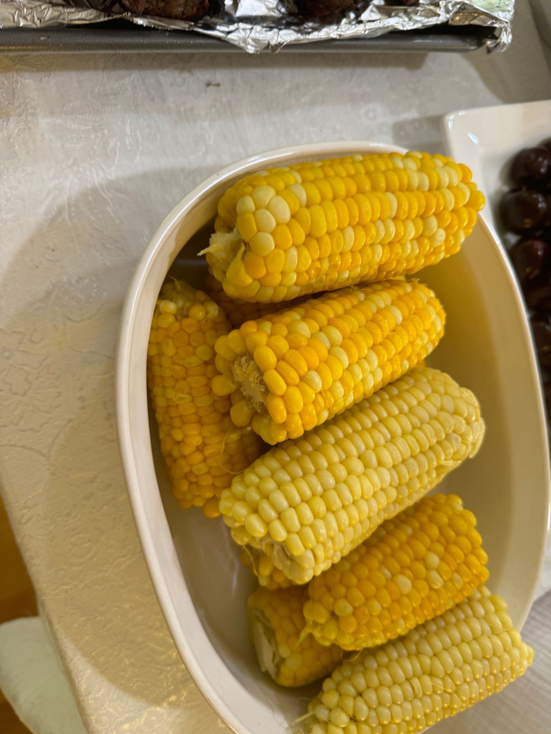 A bowl of corn on the cob is sitting on a table.