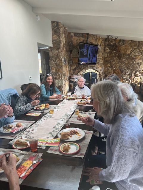 A group of people are sitting around a long table eating food.