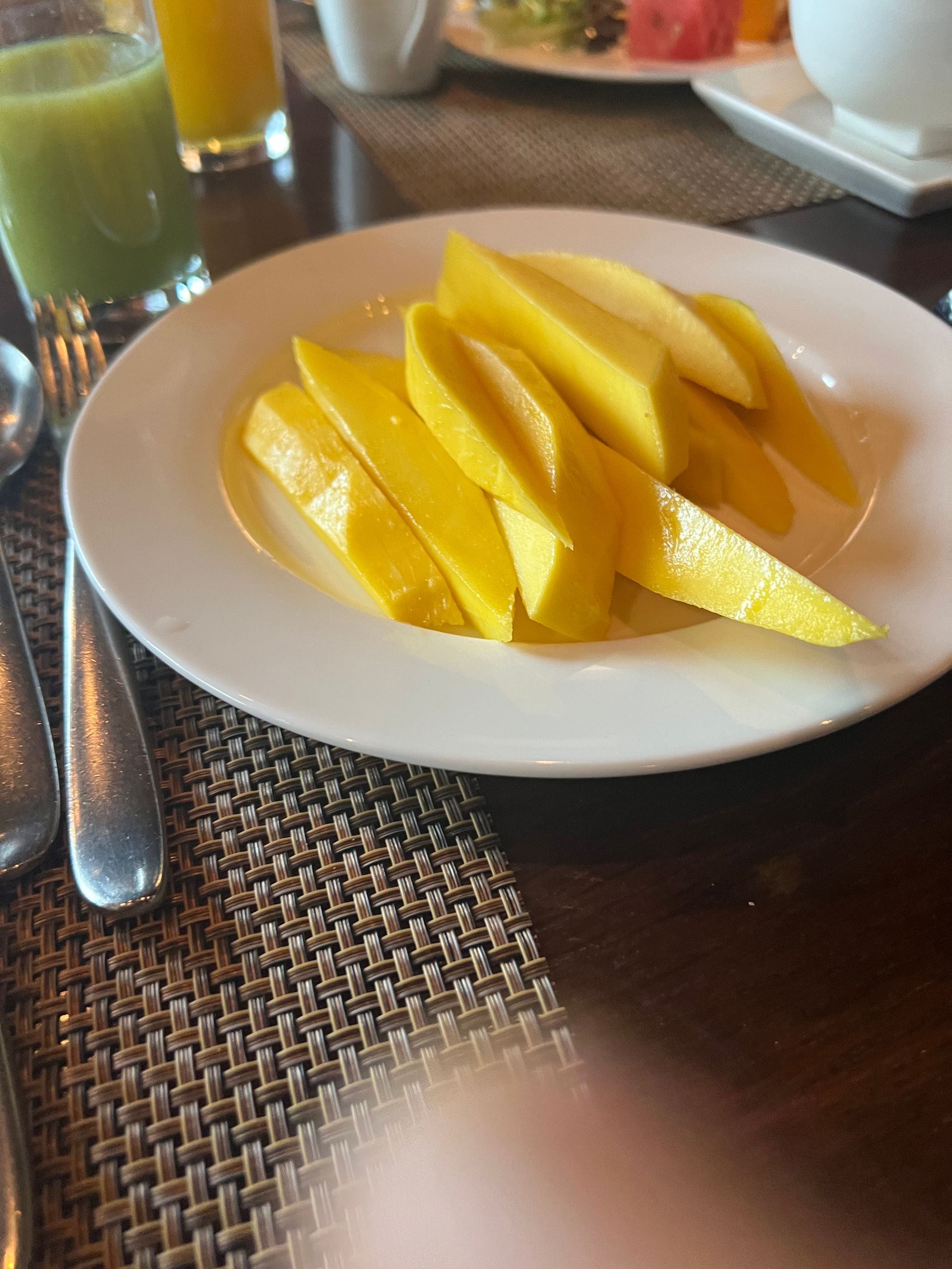 A white plate topped with sliced mangoes on a table