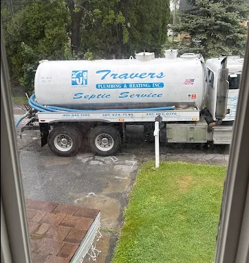 Plumber in gray overalls fixes a kitchen sink with a wrench. Tools and cleaning supplies visible.
