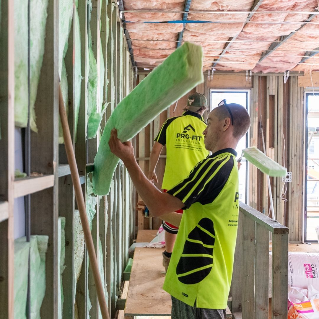 A man is holding a roll of insulation in a room.