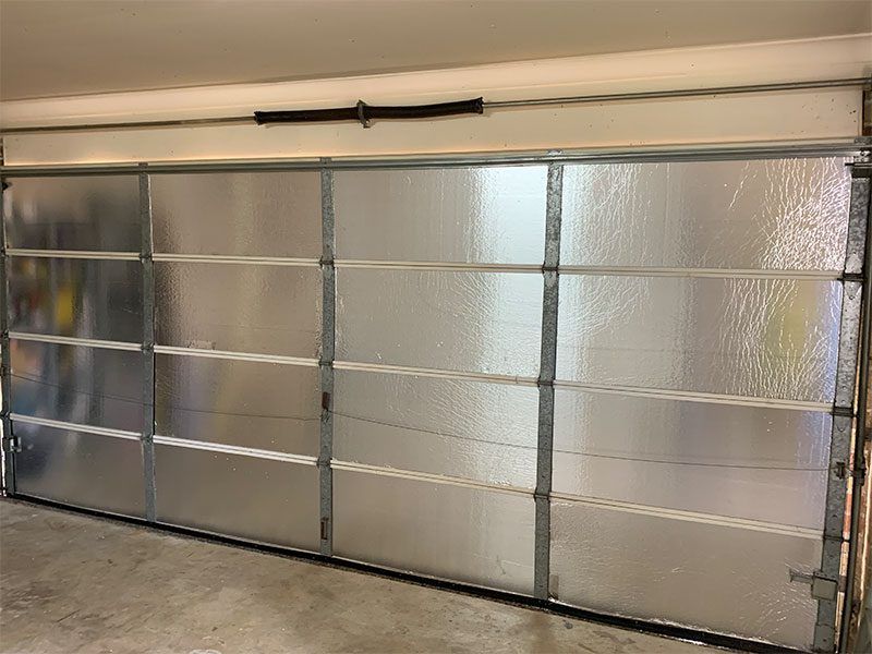 A Garage Door With A Clear Glass Door And A Spring — Pro-fit Insulation in Arundel, QLD