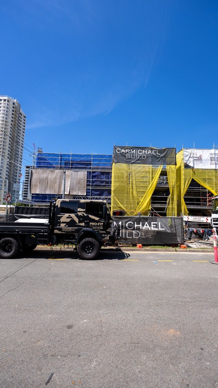 A construction site with trucks parked in front of a building — Home Insulation in Ballina NSW